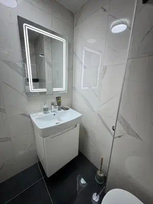 a white bathroom with a sink and a mirror at Kastel Apartmani in Banja Luka