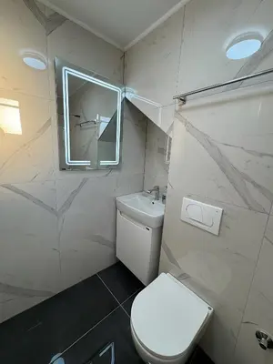 a white bathroom with a toilet and a window at Kastel Apartmani in Banja Luka