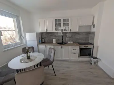 a kitchen with white cabinets and a table and chairs at Apartman Isak in Banja Luka