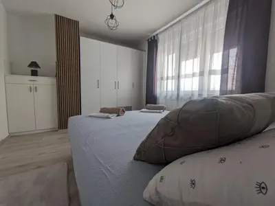 a bedroom with two beds and a large window at Apartman Isak in Banja Luka