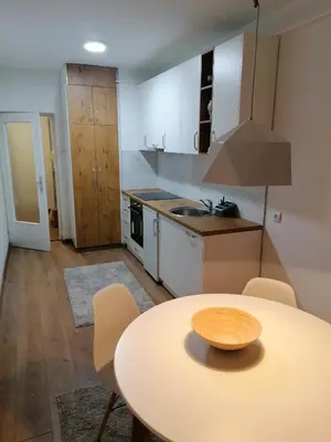 a kitchen with a table and a kitchen with white cabinets at Apartman Mina in Banja Luka
