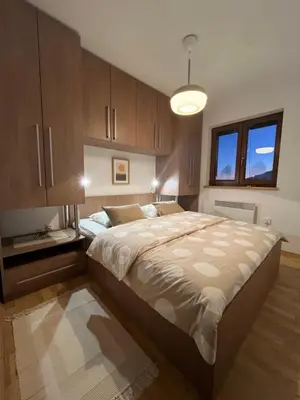 a bedroom with a large bed and wooden cabinets at Kupres Apartman555 in Kupres