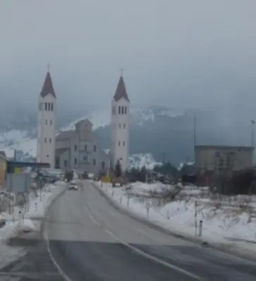 a road leading to a large building with two towers at Kupres Apartman555 in Kupres