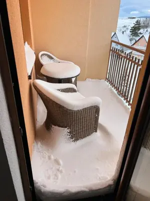two chairs on a balcony covered in snow at Kupres Apartman555 in Kupres