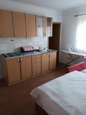 a kitchen with wooden cabinets and a sink and a bed at stidio sa 1 spavaćom sobom SM IK 4 in Tomislavgrad