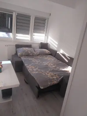 a bedroom with a bed and a couch and windows at Stan na dan in Žepče