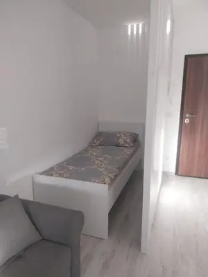 a small bedroom with a bed and a chair at Stan na dan in Žepče