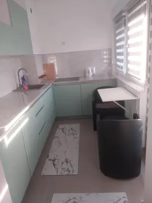 a kitchen with white cabinets and a sink and a stool at Stan na dan in Žepče