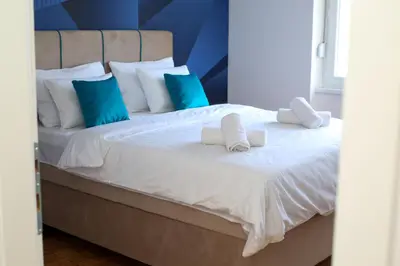 a bed with blue and white pillows on it at Apartman Paradiso in Jajce
