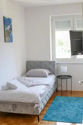 a bedroom with a bed with a blue rug and a window at Apartman Paradiso in Jajce
