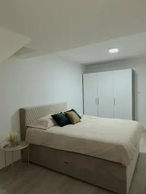 a bedroom with a large bed and a white wall at Apartman REINA HOME in Prijedor