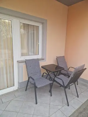 three chairs and a table on a porch with a window at APARTMAN Iva in Tomislavgrad