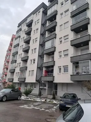 a large apartment building with cars parked in front of it at Apartmani Jaca in Tuzla