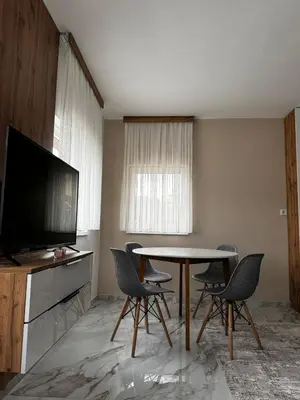 a living room with a table and chairs and a television at Crown Apartmani Vlašić in Vlasic