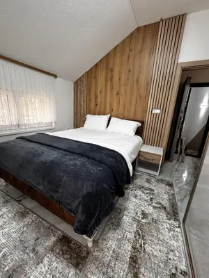 a bedroom with a large bed with a wooden wall at Crown Apartmani Vlašić in Vlasic