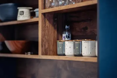 a shelf with cups and bottles on it at Container House Kod Čupe in Kupres