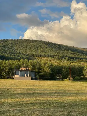 a house in a field with a hill in the background at Container House Kod Čupe in Kupres