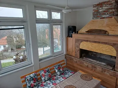 a living room with a fireplace and two windows at Vikendica Kozlovac in Tuzla