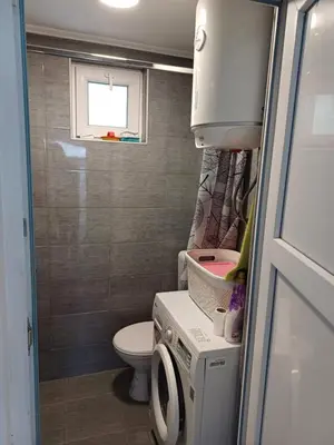 a small bathroom with a toilet and a washing machine at Vikendica Kozlovac in Tuzla