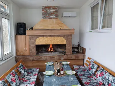 a living room with a fireplace and a table and chairs at Vikendica Kozlovac in Tuzla