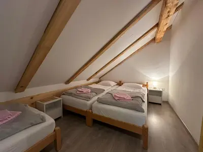 a attic room with two beds and two tables at Apartman Santro in Kupres
