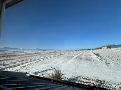 a snow covered field with a dirt road at Apartman Santro in Kupres