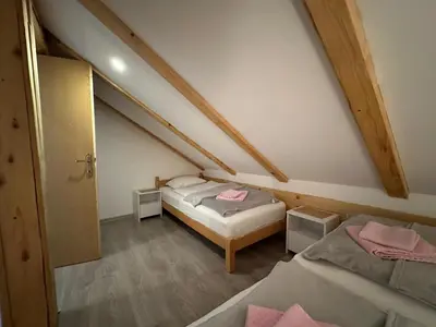a room with two beds in a attic at Apartman Santro in Kupres
