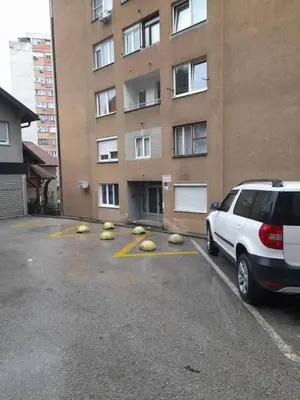 a car parked in a parking lot in front of a building at Palma Apartman in Tuzla