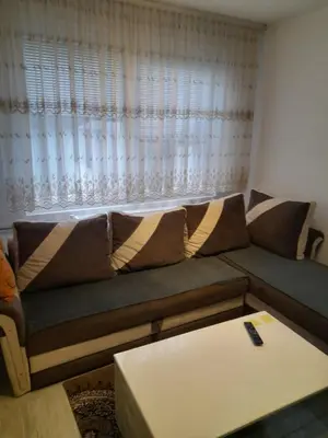 a living room with a couch in front of a window at Palma Apartman in Tuzla