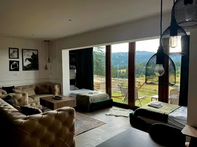 a living room with a couch and a large window at Pine apartment Vlašić in Vlasic