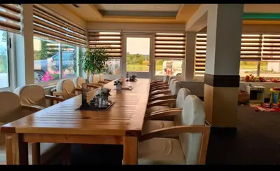 a long wooden table and chairs in a room with windows at Motel i Restoran Ana in Donji Svilaj