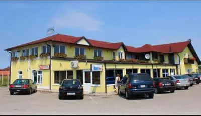 a yellow building with cars parked in a parking lot at Motel i Restoran Ana in Donji Svilaj