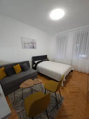 a bedroom with a bed and a couch and chairs at Stan na dan G & V in Prijedor