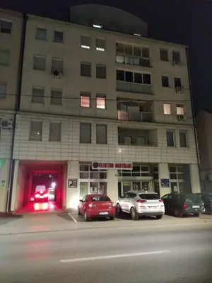 a large building with cars parked in a parking lot at Stan na dan G & V in Prijedor
