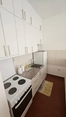 a white kitchen with a stove and white cabinets at Stan na dan G & V in Prijedor