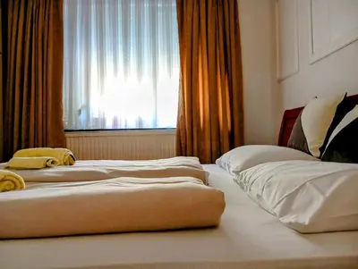 two beds in a hotel room with a window at Dnevna Soba in Doboj