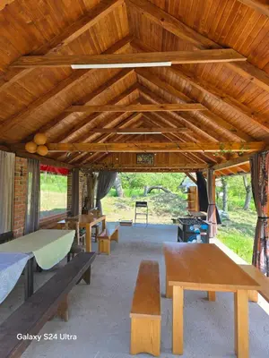 a group of picnic tables and benches under a wooden roof at Vikendica sa djakuzijem Borik in Grabova Kosa