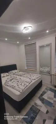 a bedroom with a large bed and two windows at STUDIO APARTMAN SOl in Tuzla