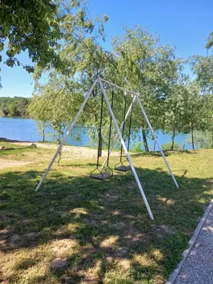 a swing set in the grass next to the water at Una, Home on river bank in Spilja