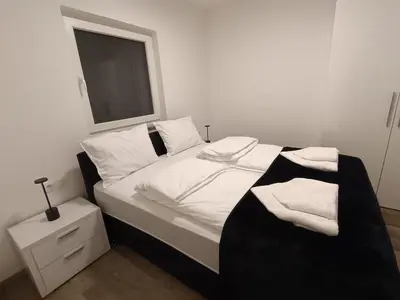 a bedroom with a bed with white sheets and a window at White Queen Apartments 1 in Sanski most