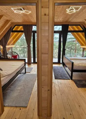 two beds in a room with wooden floors and windows at Villa Pine in Lukavac