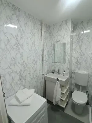 a white bathroom with a toilet and a sink at Srce grada Gradiška in Bosanska Gradiška