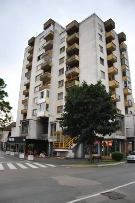 a large white building with balconies on a street at Srce grada Gradiška in Bosanska Gradiška