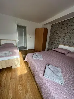 two beds in a bedroom with purple sheets and towels at White house in Bihać