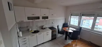 a kitchen with white cabinets and a small table with a table at Apartments Padrino BP in Bosanski Novi
