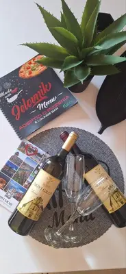 a table with two bottles of wine and a glass at Apartments Padrino BP in Bosanski Novi