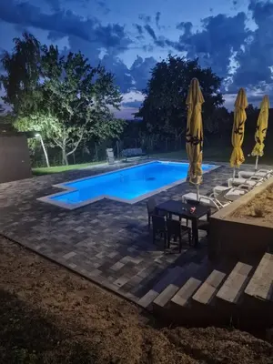 a swimming pool with a table and umbrellas at Vikendica El Paradiso Banjaluka in Laktaši