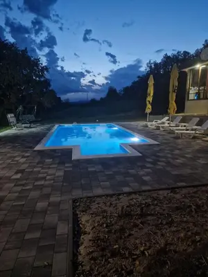 a swimming pool in a backyard at night at Vikendica El Paradiso Banjaluka in Laktaši