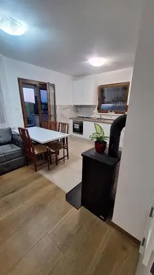 a living room with a table and a kitchen at Vikendica El Paradiso Banjaluka in Laktaši