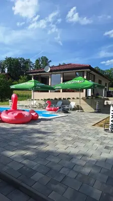 a swimming pool with some inflatablelatableoses and green umbrellas at Vikendica El Paradiso Banjaluka in Laktaši